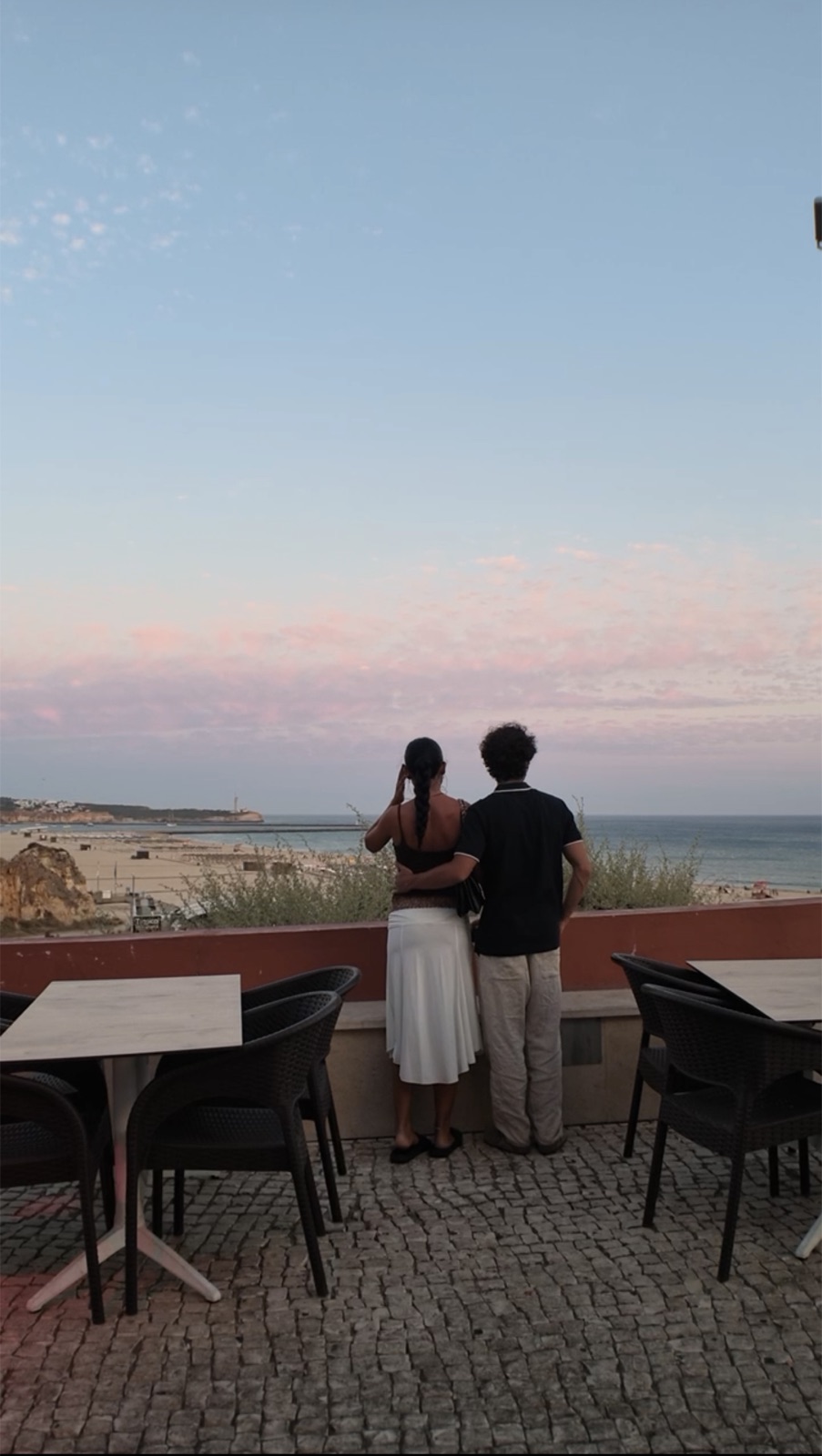 Josh and Jess overlooking the ocean at sunset while traveling